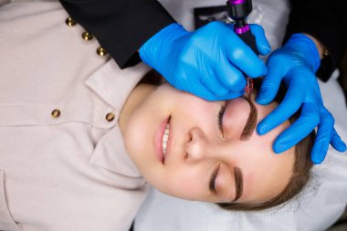 Güzellik salonunda gür kaşları olan güzel bir kadının yüzü. Kaşlar için kalıcı makyaj. Güzellik uzmanı kadınlar için kaş dövmesi yapar. Güzellik prosedürü.