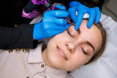 Güzellik salonunda gür kaşları olan güzel bir kadının yüzü. Kaşlar için kalıcı makyaj. Güzellik uzmanı kadınlar için kaş dövmesi yapar. Güzellik prosedürü.