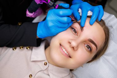 Güzellik salonunda gür kaşları olan güzel bir kadının yüzü. Kaşlar için kalıcı makyaj. Güzellik uzmanı kadınlar için kaş dövmesi yapar. Güzellik prosedürü.