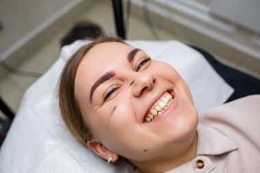 Kaşlarında kalıcı makyaj dövmesi olan bir kadın. Yakın plan güzellik uzmanı makyajı bir temele uygular. Profesyonel makyaj ve estetik cilt bakımı.