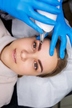 Yüzünde kalıcı makyajın lazerle çıkarılması. Dövme yaptıran genç bir kadının yakın çekimi. Yüzündeki doğal kusurların düzeltilmesi.