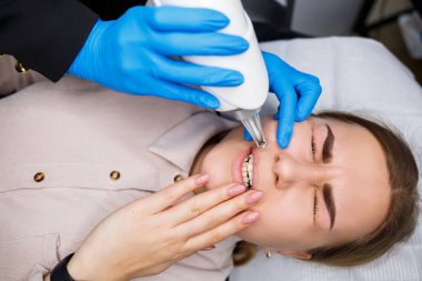 Yüzünde kalıcı makyajın lazerle çıkarılması. Dövme yaptıran genç bir kadının yakın çekimi. Yüzündeki doğal kusurların düzeltilmesi.