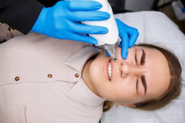 Yüzünde kalıcı makyajın lazerle çıkarılması. Dövme yaptıran genç bir kadının yakın çekimi. Yüzündeki doğal kusurların düzeltilmesi.