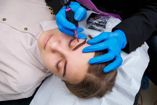 Güzellik salonunda gür kaşları olan güzel bir kadının yüzü. Kaşlar için kalıcı makyaj. Güzellik uzmanı kadınlar için kaş dövmesi yapar. Güzellik prosedürü.
