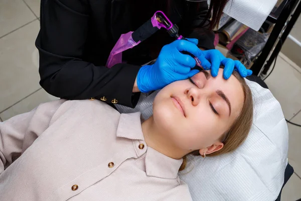 Güzellik salonunda gür kaşları olan güzel bir kadının yüzü. Kaşlar için kalıcı makyaj. Güzellik uzmanı kadınlar için kaş dövmesi yapar. Güzellik prosedürü.