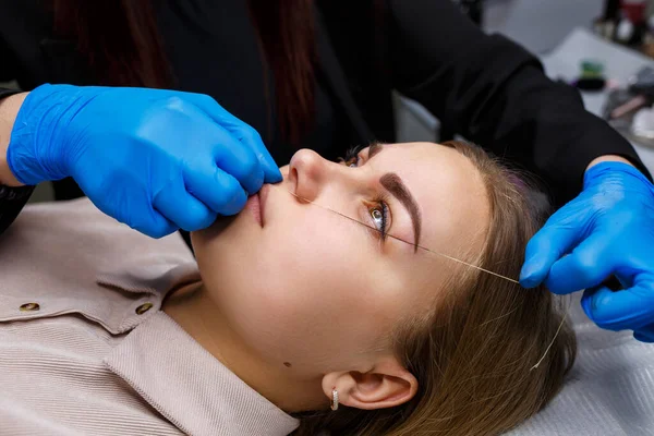 Kaşlarında kalıcı makyaj dövmesi olan bir kadın. Güzellik uzmanı kaşların bir taslağını çiziyor. Profesyonel makyaj ve estetik cilt bakımı.