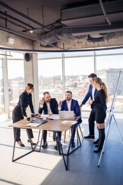 İş, teknoloji ve ofis kavramı. Laptop bilgisayarlı, belgeli ve kahveli mutlu iş adamları. İş gününden önce bir iş planı tartışmak için toplanıyoruz.