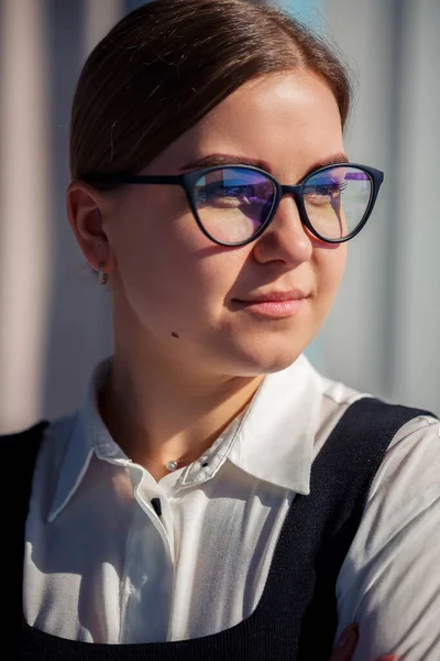 Confident business woman boss standing in modern office wearing glasses, female leader, business owner thinking about future success, planning new opportunities