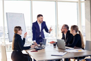 Şehir manzaralı modern bir ofiste birlikte çalışan iş adamları. Müdür personele yeni teknolojilerden bahsediyor. Ofis işi kavramı
