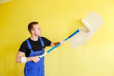 Genç bir adam daireyi onarıyor, tamam mı? Duvarları farklı renkte boyuyor.