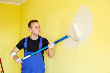 Genç bir adam daireyi onarıyor, tamam mı? Duvarları farklı renkte boyuyor.