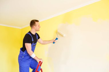 Erkek uzman duvarları kapalı alanda boyuyor, tamir konsepti var.