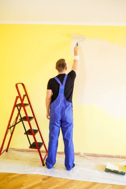 Erkek uzman duvarları kapalı alanda boyuyor, tamir konsepti var.
