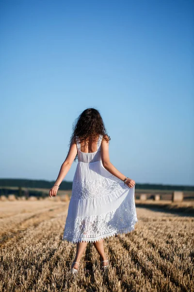 一个身穿白色夏装的年轻漂亮的女人站在割了大捆干草的麦田上 享受大自然的美景 村里的自然 有选择的重点 — 图库照片