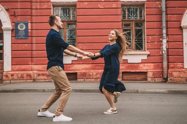 一对恋爱中的快乐的已婚夫妇在街上跑来跑去 兴高采烈 美丽的年轻夫妇手牵手 微笑着沿着城市街道走着 — 图库照片