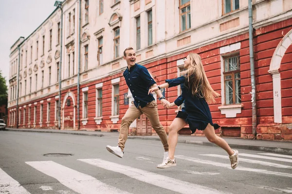 一对恋爱中的快乐的已婚夫妇在街上跑来跑去 兴高采烈 美丽的年轻夫妇手牵手 微笑着沿着城市街道走着 — 图库照片