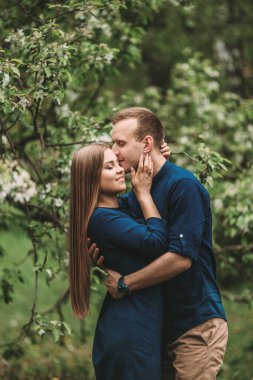 Bahar bahçesinde elinde kız olan yakışıklı bir genç. Romantik çift parkta yürüyor. Mutlu İlişkiler