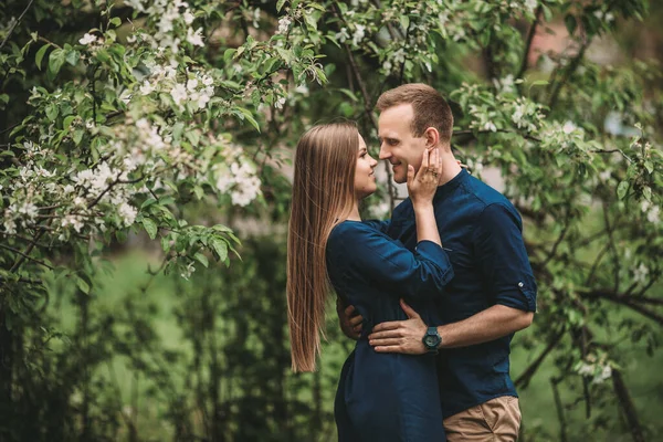 春の庭に女の子とハンサムな若い男が立っている ロマンチックなカップルが公園を歩いている 幸せな関係の概念 — ストック写真