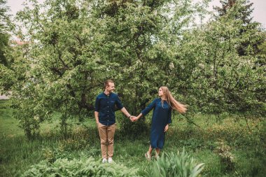 Bahar bahçesinde elinde kız olan yakışıklı bir genç. Romantik çift parkta yürüyor. Mutlu İlişkiler