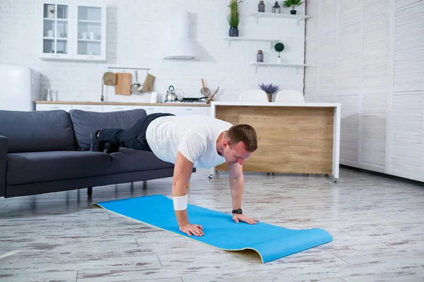 A young man goes in for sports at home, he does push-ups on the couch. Healthy lifestyle