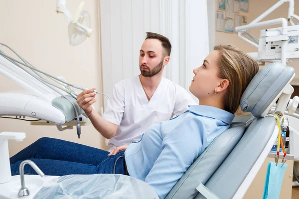 A professional dentist communicates with a woman patient. Dental office for patient examination. Discussion of the dental treatment process.