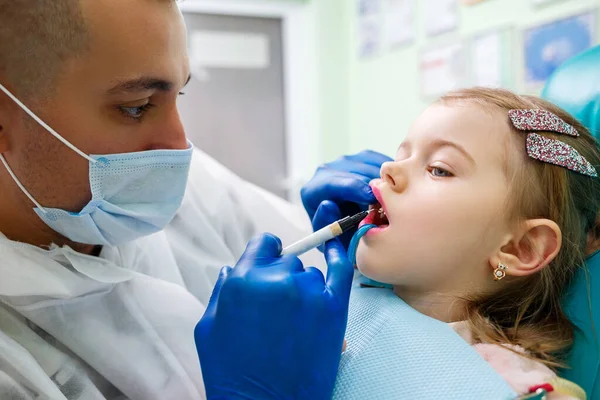 一个专业的医生 一个儿童牙医 用仪器治疗小女孩的牙齿 牙科诊所为病人检查 儿童的牙科治疗过程 — 图库照片