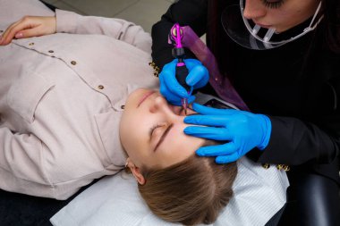 Güzellik salonunda gür kaşları olan güzel bir kadının yüzü. Kaşlar için kalıcı makyaj. Güzellik uzmanı kadınlar için kaş dövmesi yapar. Güzellik prosedürü.