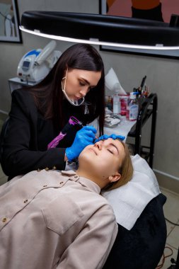 Güzellik salonunda gür kaşları olan güzel bir kadının yüzü. Kaşlar için kalıcı makyaj. Güzellik uzmanı kadınlar için kaş dövmesi yapar. Güzellik prosedürü.