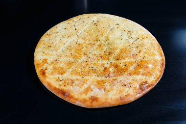 Siyah taşlı arka planda dilimlenmiş pizza, üst manzara. Peynirli taze pişmiş Focaccia.