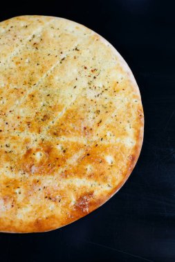 Siyah taşlı arka planda dilimlenmiş pizza, üst manzara. Peynirli taze pişmiş Focaccia.