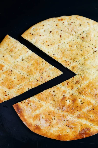 Pokrojona pizza na czarnym kamiennym tle, widok z góry. Świeżo upieczona focaccia z serem — Zdjęcie stockowe