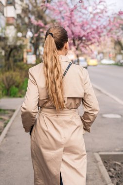 Sakura ağaçlarının yanında güzel bir kadın. Şehir caddesindeki ağaçlarda pembe çiçekler açar. Ağaçlar çiçek açar. Bahar zamanı konsepti