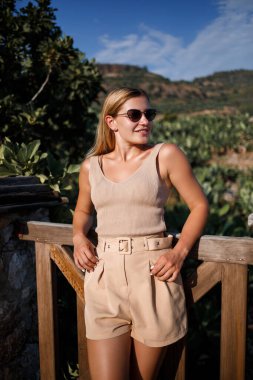 Genç ve güzel bir kadın, yeşil koruluğun çarpıcı manzarasıyla gözlem güvertesinde duruyor.