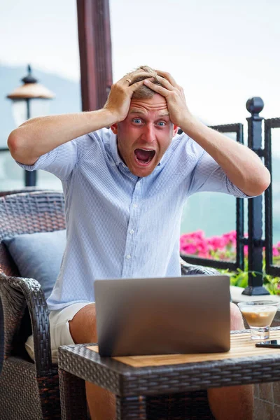 Duygusal bir adam tatilde bilgisayarın başına oturur ve çalışır. Freelancer tatildeyken çalışıyor — Stok fotoğraf