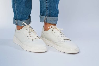 Erkeklerin ayakları günlük beyaz spor ayakkabılarla bağcıklı doğal deriden yapılmış. Yüksek kalite fotoğraf