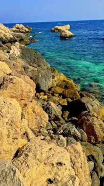 Kayalık oluşumlar parlak mavi bir gökyüzü altında berrak turkuaz suyla harmanlanır. Kıyı şeridi eşsiz taşlara ve nazik dalgalara sahiptir. Keşif ve sükuneti davet eder.