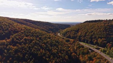 Altın sonbahar yaprakları sarar yuvarlanan tepeleri dolambaçlı bir yol yemyeşil vadiden geçer ve uzak tepeler yükselir yumuşak bulutlarla dolu parlak bir gökyüzüne doğru