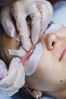 Yetenekli bir teknisyen, müşterinin gözlerine belirli alet ve teknikler kullanarak kirpik eklentisi uygular. Kuaför salonu sıcak ve davetkar, umut verici bir rahatlama..