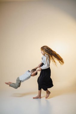 İki çocuk, biri diğerinin elini tutarken eğlenceli bir anı paylaşır. Kahkahaları parlak stüdyoyu dolduruyor, tasasız bir çocukluk ortamı yaratıyor..