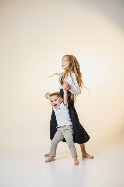 Işıl ışıl, yumuşak bir sahnede neşeyle dans eden iki kardeş aynı zevkli anı paylaşıyor. Kahkahaları havayı dolduruyor, çocukluk sevincinin ve özgürlüğün özünü yakalıyor..