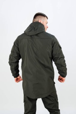 İzleyiciye arkası dönük, parlak, koyu renk ceketli bir adam. Duruşu, ceketin tasarımını ve etrafındaki minimalist stüdyo ortamını vurguluyor..