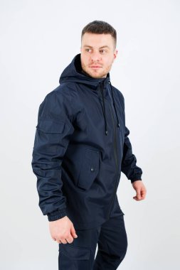 Bir adam temiz, modern bir mekanda donanma ceketini gösteriyor. Rahat duruşu ve kendine güveni güneşli bir günde bir tarz ve rahatlık hissi yakalıyor..