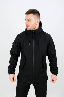 Adam parlak siyah bir ceketle, soğuk günler için çağdaş modaya dikkat çekiyor. Ayar parlak ve minimalistik, görünüşü güçlendiriyor..
