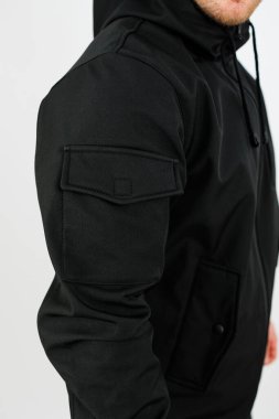 Bir model, modern bir şehir ortamında günlük geziler ve günlük giysiler için mükemmel, pratik cepleri ve şık tasarımı olan modaya uygun siyah bir kapüşonluyu sergiliyor..