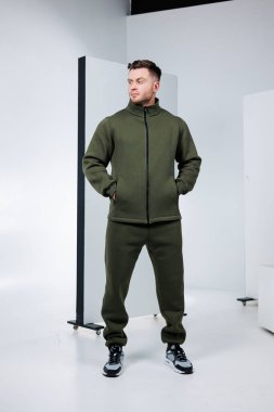 Bir adam, çağdaş bir tarzı yansıtan gösterişli bir spor kıyafeti içinde güven içinde poz verir. Temiz stüdyo ayarları onun gündelik ama modaya uygun görünümünü vurguluyor. Aktif anlar için mükemmel..