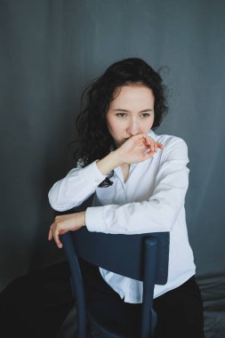 Eserde, sahnenin duygusal derinliğini arttıran, yumuşak gri bir arka plana karşı tefekkür eden, basit beyaz gömlekli düşünceli bir kadın yer alıyor.