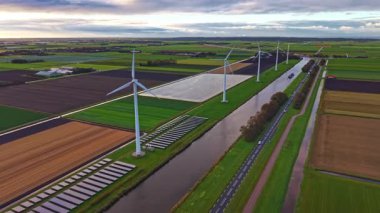 Bereketli yeşil tarlalar ve renkli tarım arazileri geniş bir görüş alanına sahiptir. Rüzgâr türbinleri rüzgarın esintisinde kıvrımlı bir kanal boyunca yavaşça dönerler..