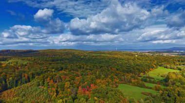 Sonbahar renkleriyle bezenmiş bereketli ormanların geniş manzarası, güneş ışığıyla yıkanmış bulutlar huzurlu kırsal alanların ve uzak tepelerin üzerinde sürükleniyor..