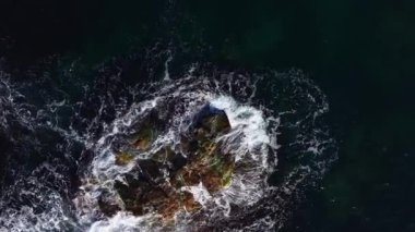 Dalgalar etraflarını sardığında kayalar okyanustan çıkar ve dinamik bir doğa gösterisi yaratır. Sahne, şafak vakti denizin büyüleyici güzelliğini yakalar, sakinliği ve enerjiyi yansıtır..