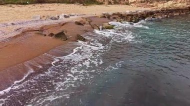 Güneş batmaya başladığında, dalgalar yavaşça kumlu kıyılara çarpar ve sakin plajda sıcak bir parıltı yayar. Kayalar manzarayı süsler, güzel bir kıyı manzarası yaratır..